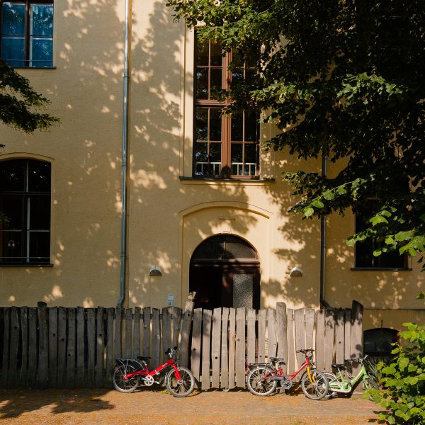 Eingang zur Kita "Treffpunkt Linde", dieser wird von einem Zaun mit Kinder-Fahrrädern leicht verdeckt.
