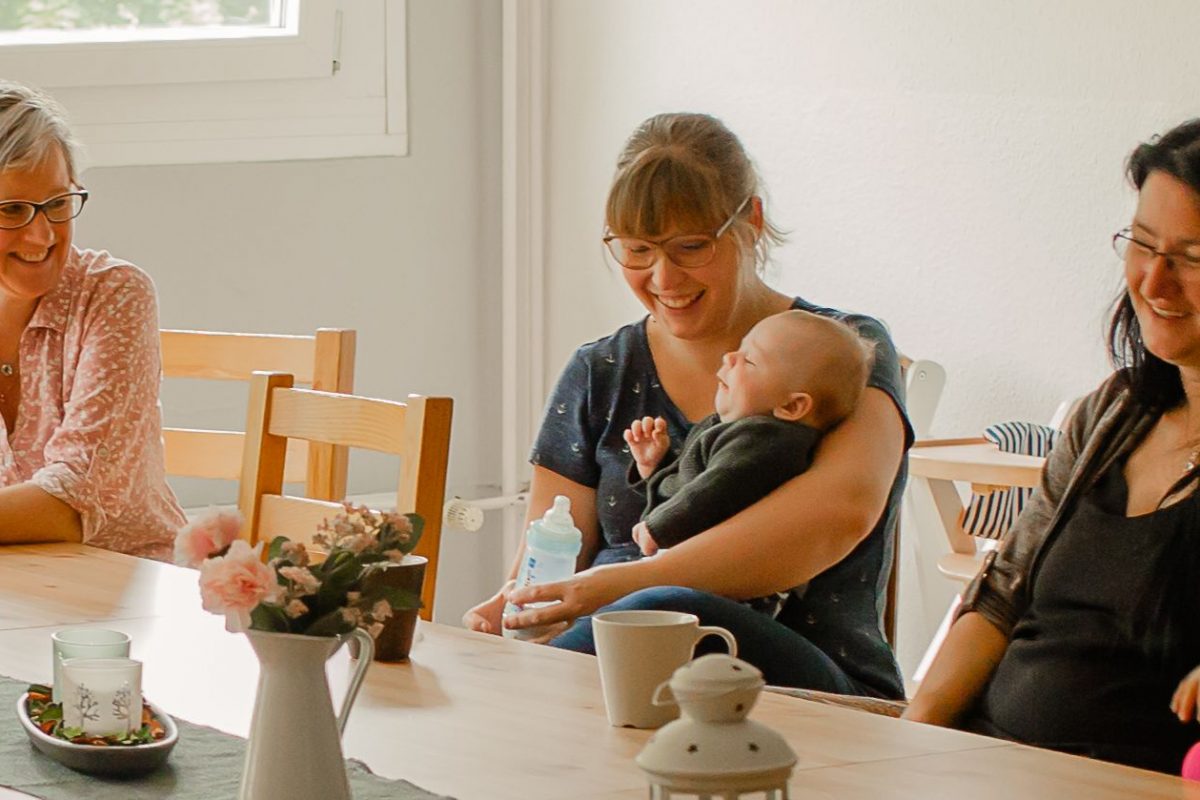 Mütter und ihre Kinder sitzen am Tisch und lachen