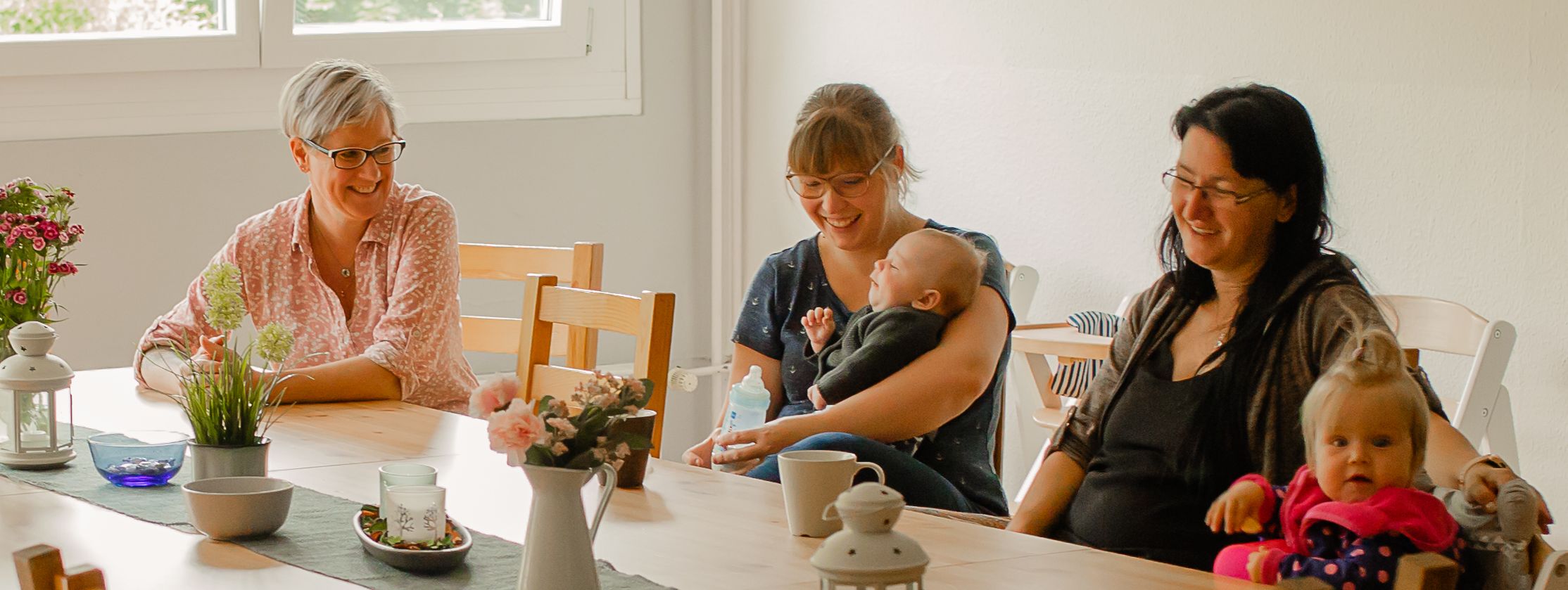 Mütter und ihre Kinder sitzen am Tisch und lachen
