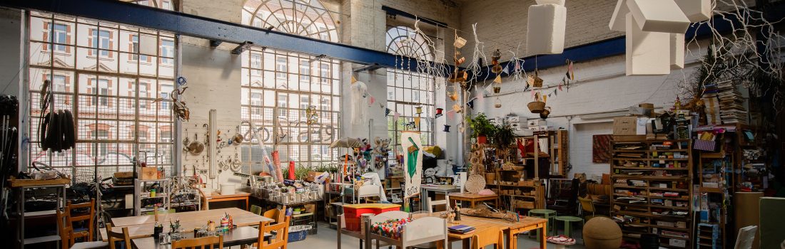 Restloshalle von innen mit Tischen, Stühlen, Regalen und Upcycling-Materialien.