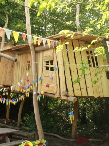 Ein Kinder-Baumhaus, geschmückt mit bunten Wimpelketten