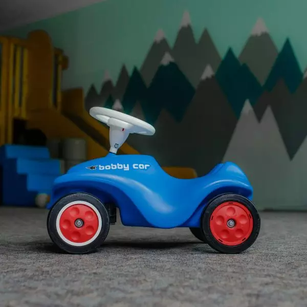 Ein blaues Bobbycar mit roten Rädern.