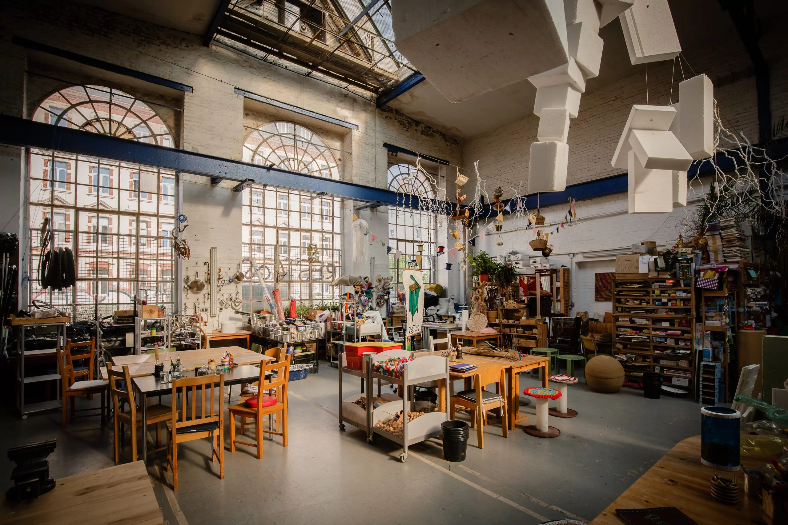 Restloshalle von innen mit Tischen, Stühlen, Regalen und Upcycling-Materialien.