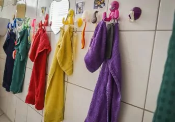 Bunte Handtücher hängen an Fliesen im Badezimmer.