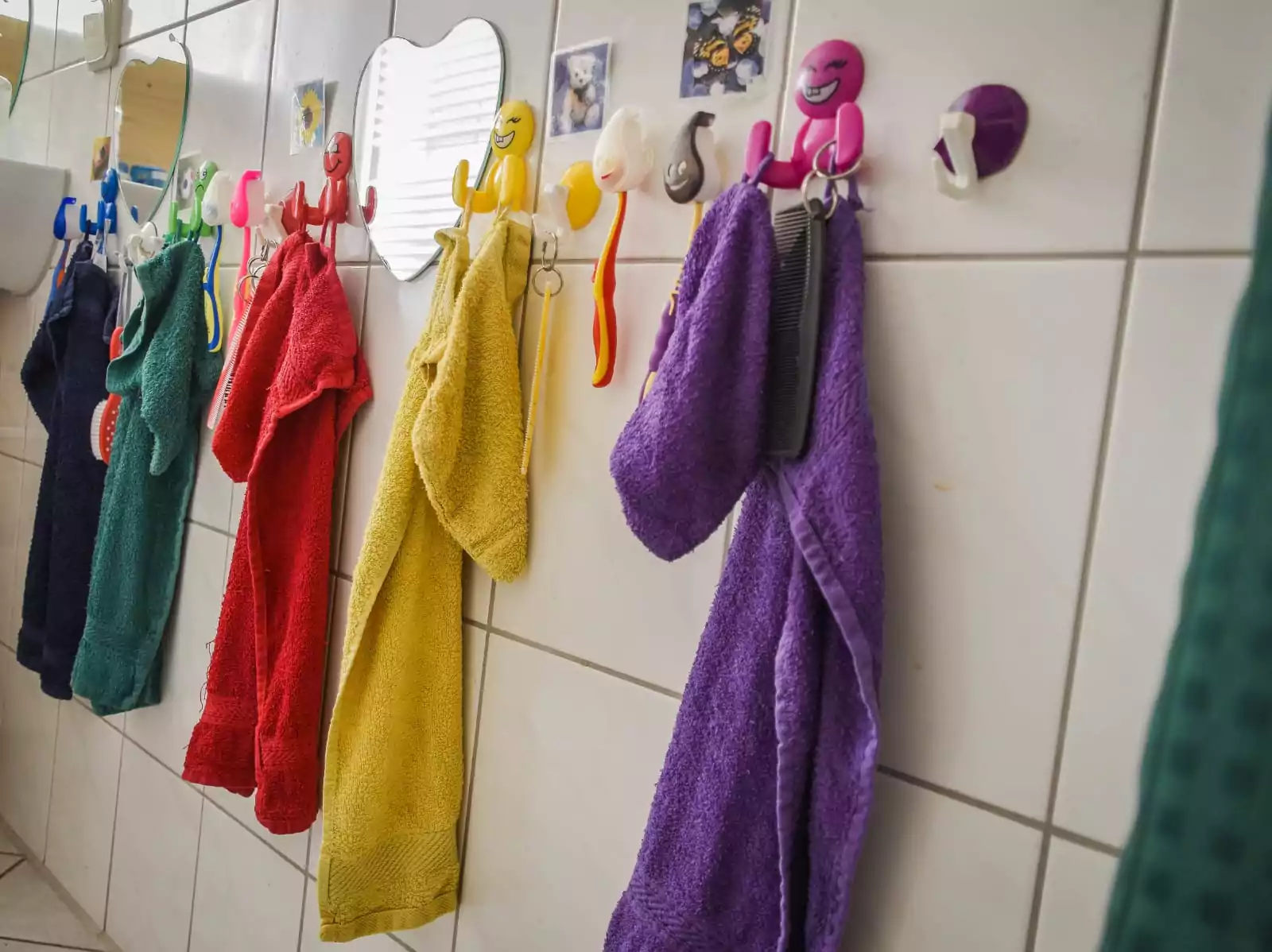 Bunte Handtücher hängen an Fliesen im Badezimmer.