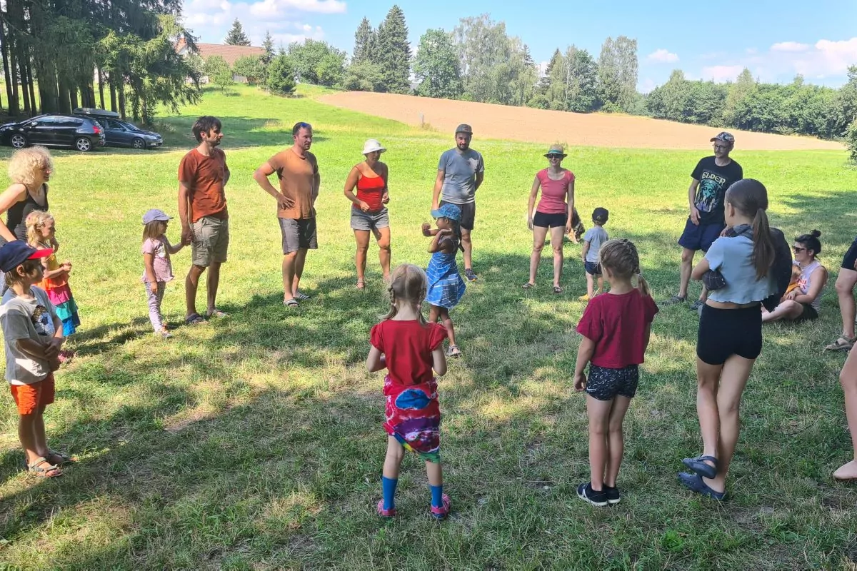 viele erwachsene Menschen und Kinder stehen in einem großen Kreis auf einer Wiese