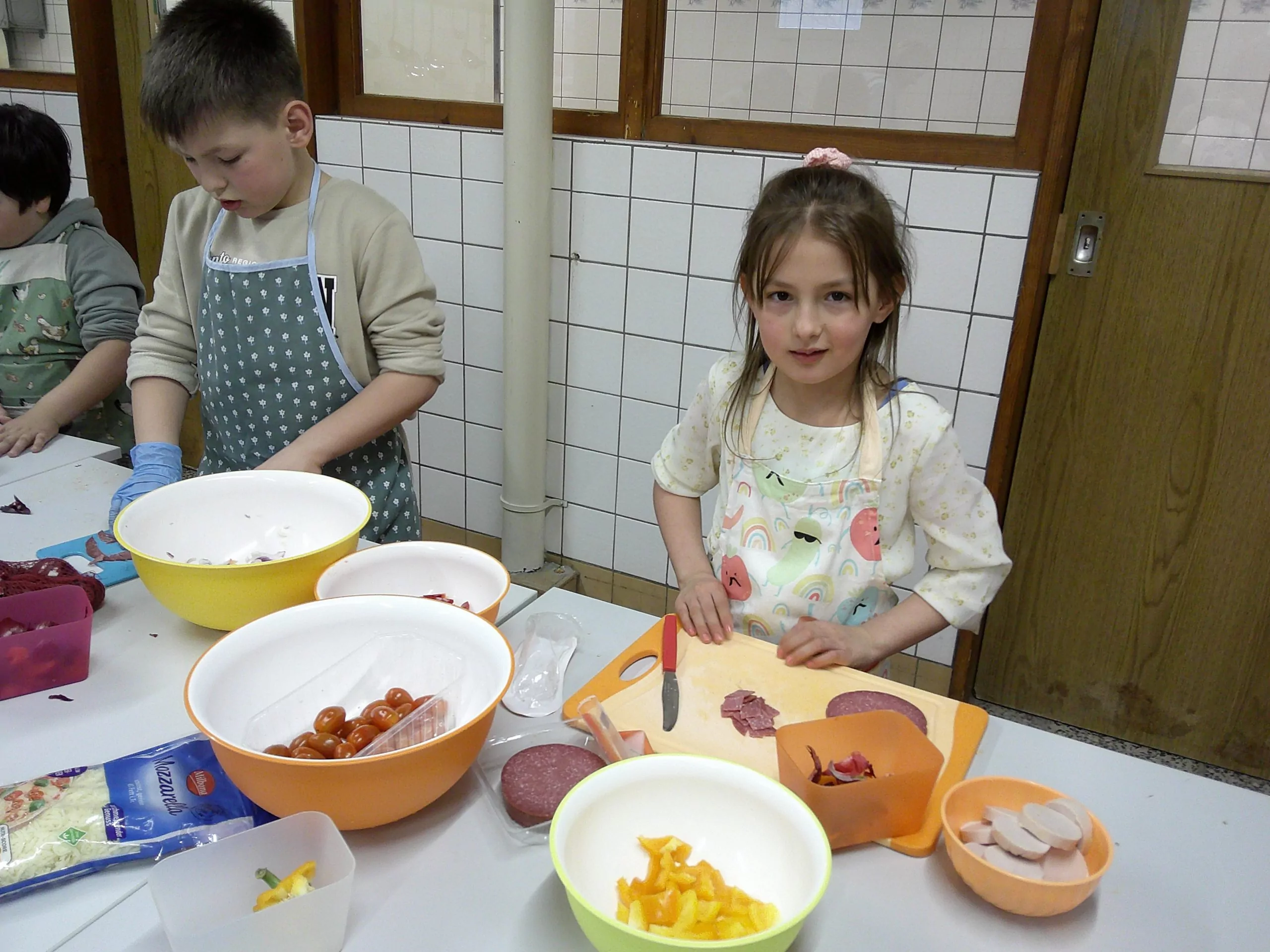 Kinder in der Paunsdorfer KiFaZ-Kita „Kleine Entdecker“ schneiden Paprika, Tomaten und Salami zum Belegen der Pizzen klein.